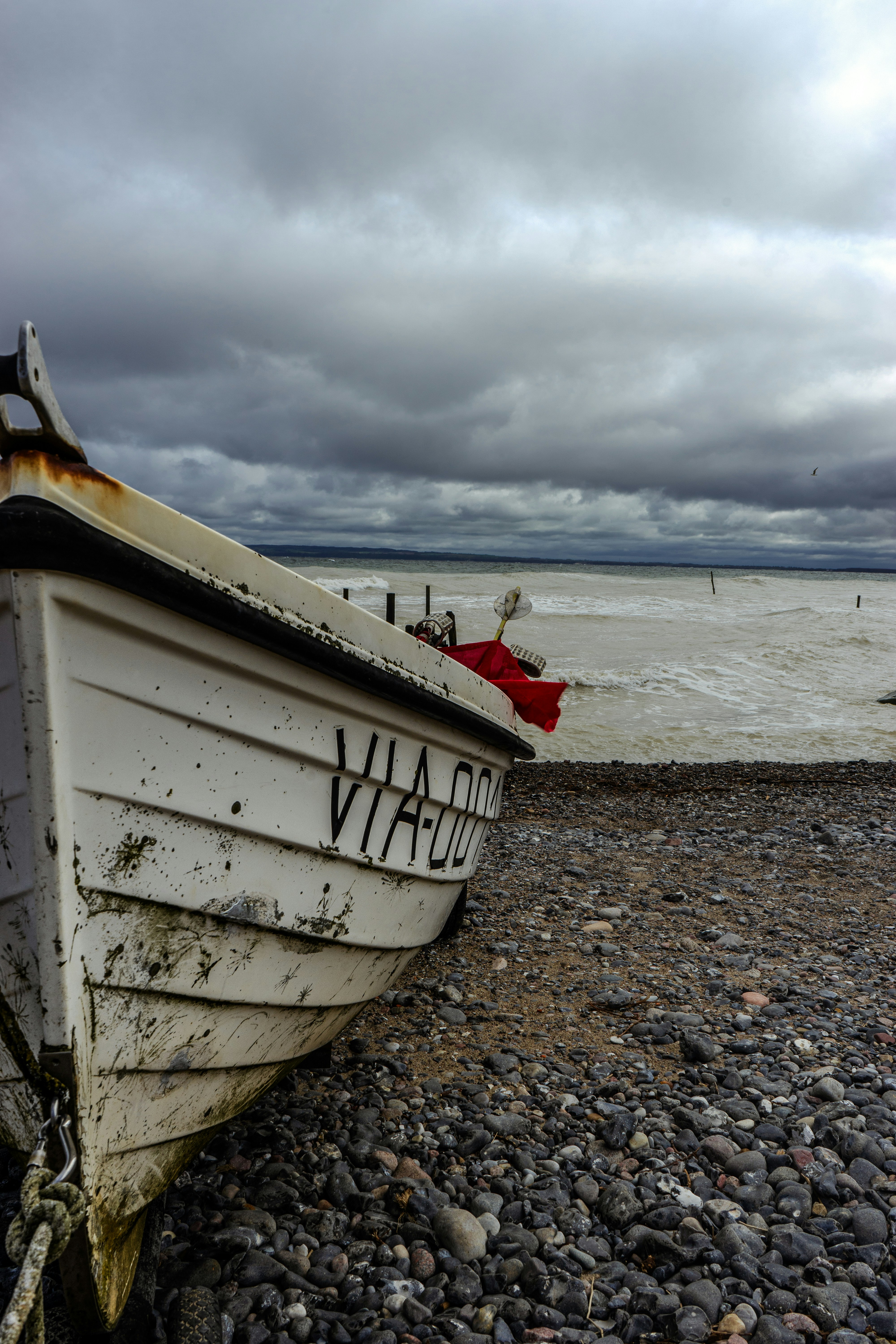 um barco branco sentado no topo de uma praia rochosa