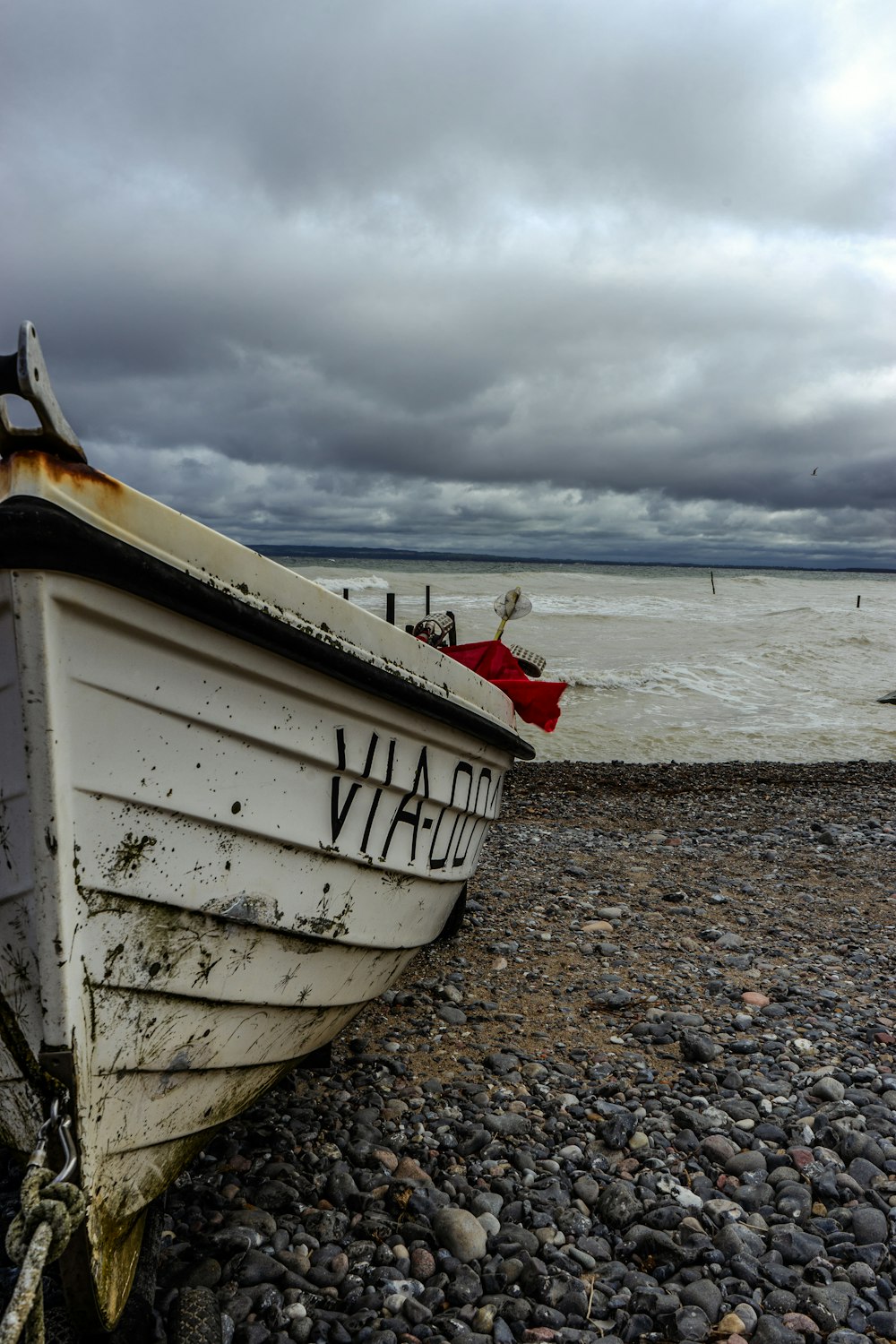 a white boat sitting on top of a rocky beach