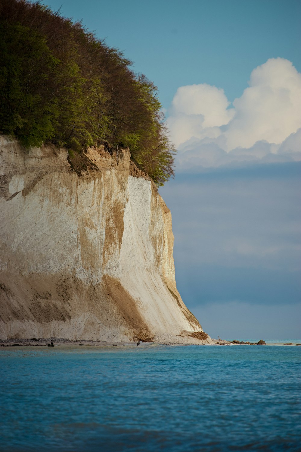 a beach with a cliff and a body of water