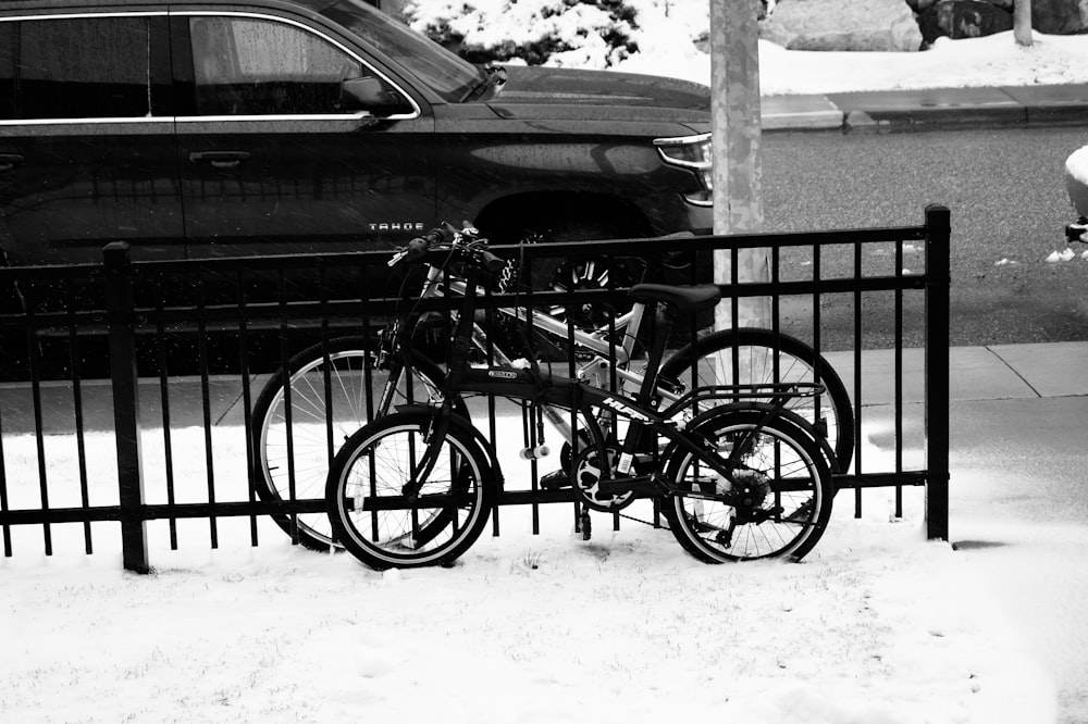 a black and white photo of a bike parked next to a fence