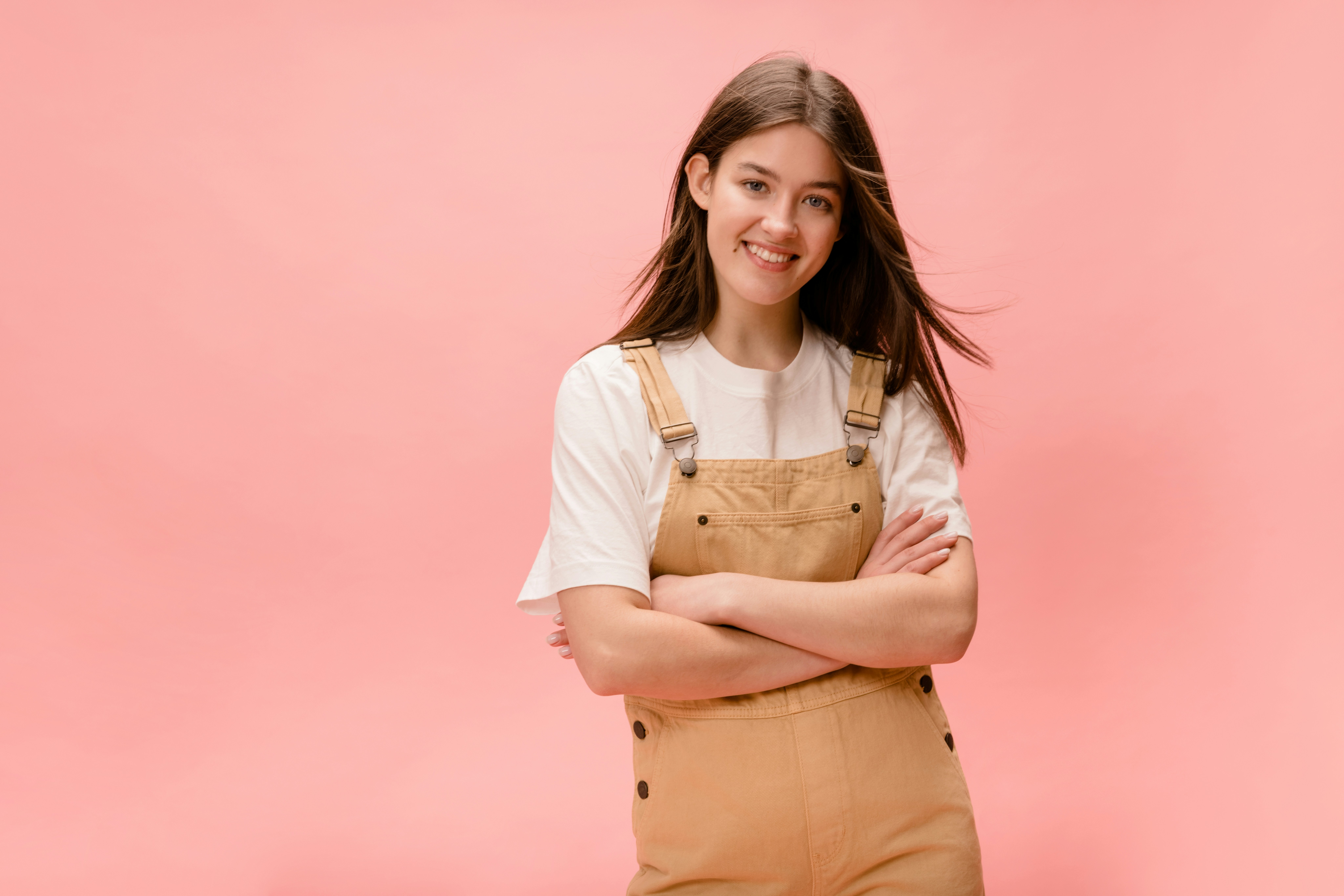 a woman in overalls standing with her arms crossed