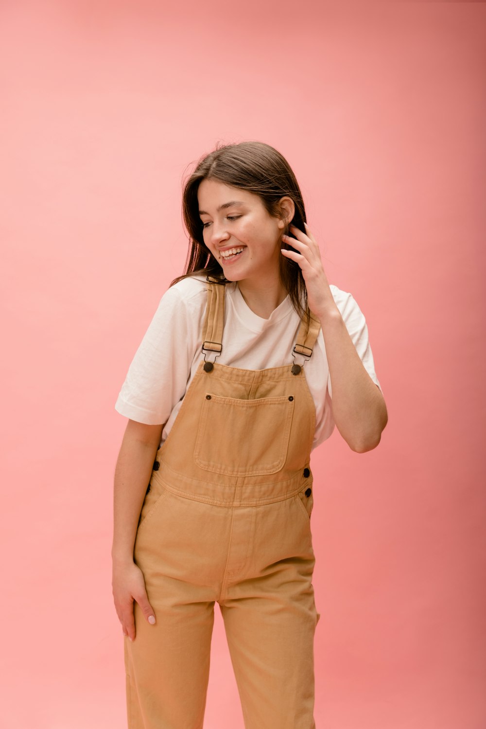 a woman in overalls talking on a cell phone