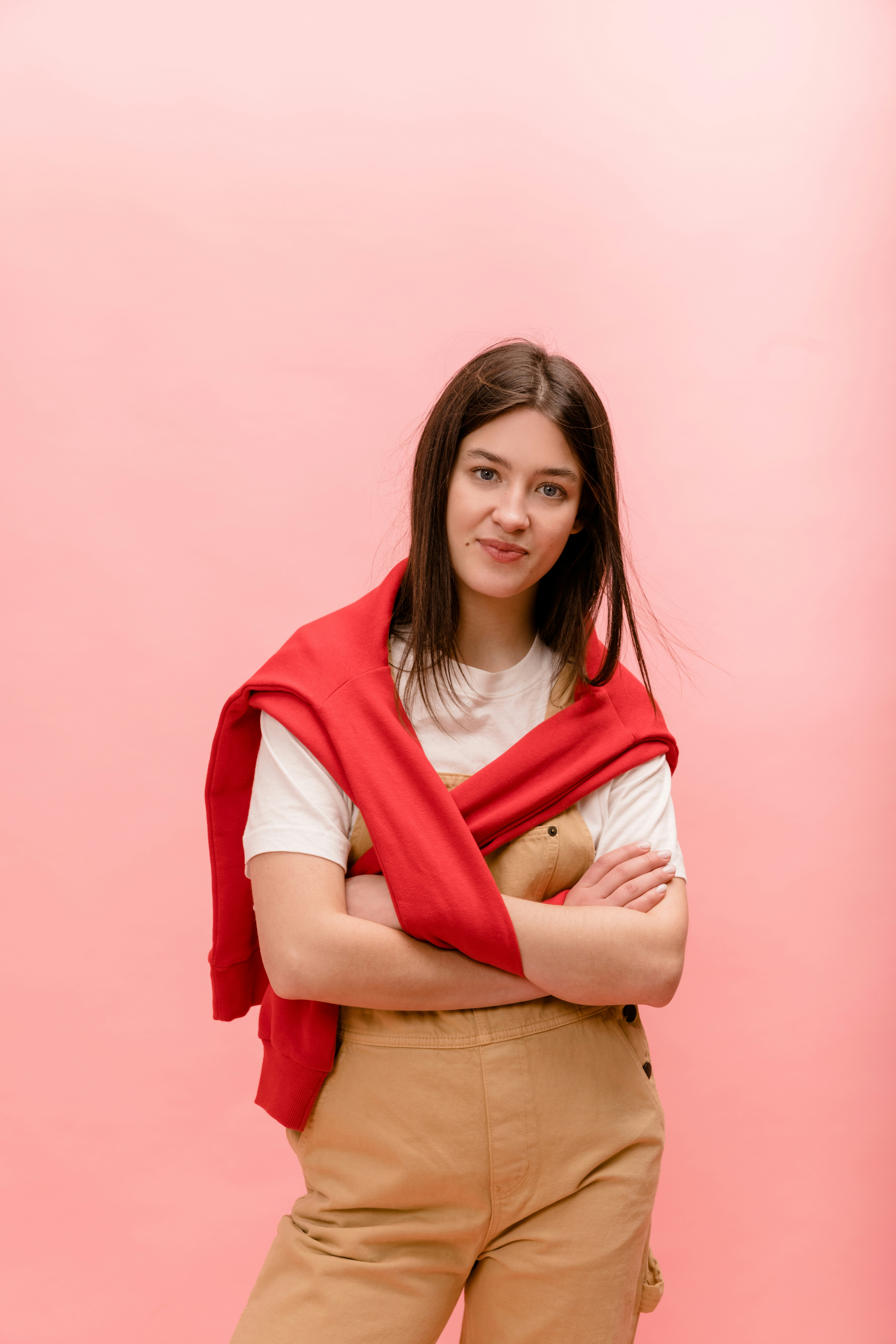 a woman standing with her arms crossed wearing a red scarf