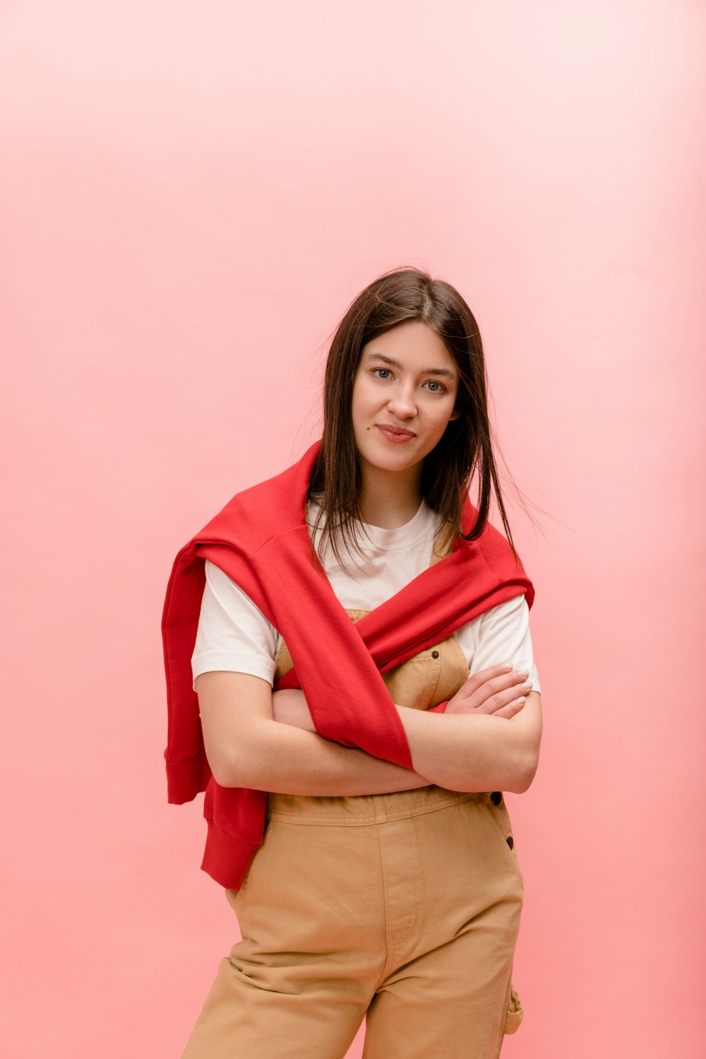 a woman standing with her arms crossed wearing a red scarf