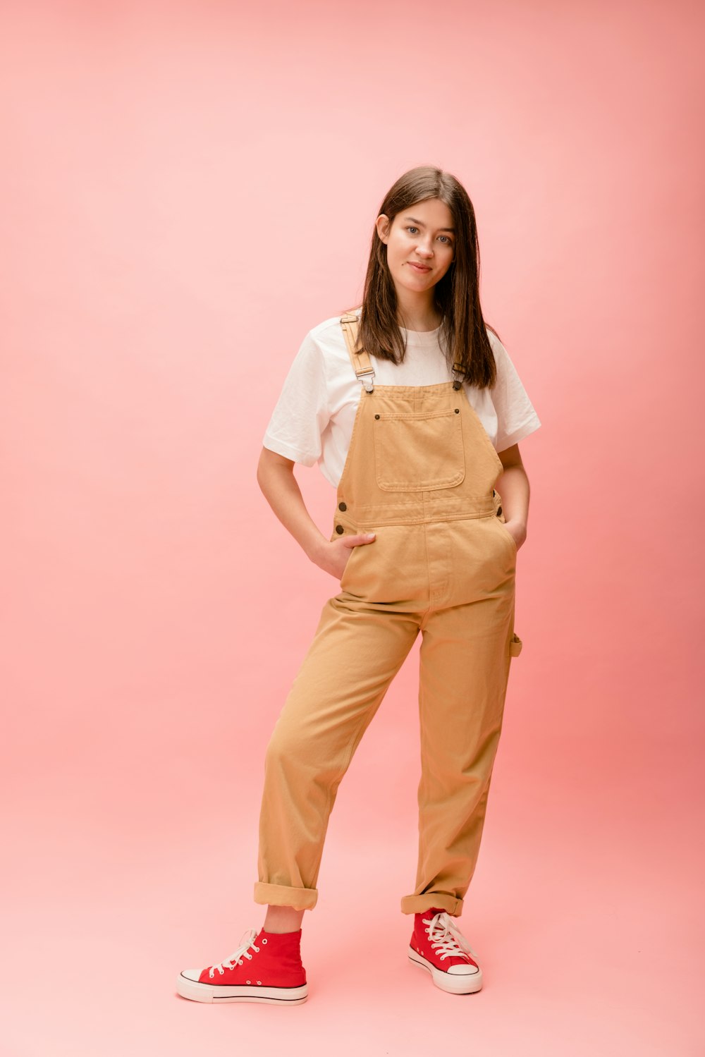 a woman in a white shirt and tan overalls