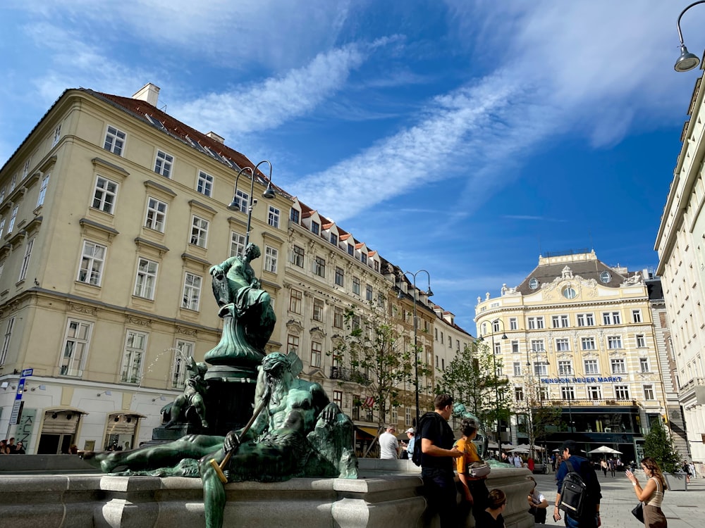 a group of people standing around a fountain in a city