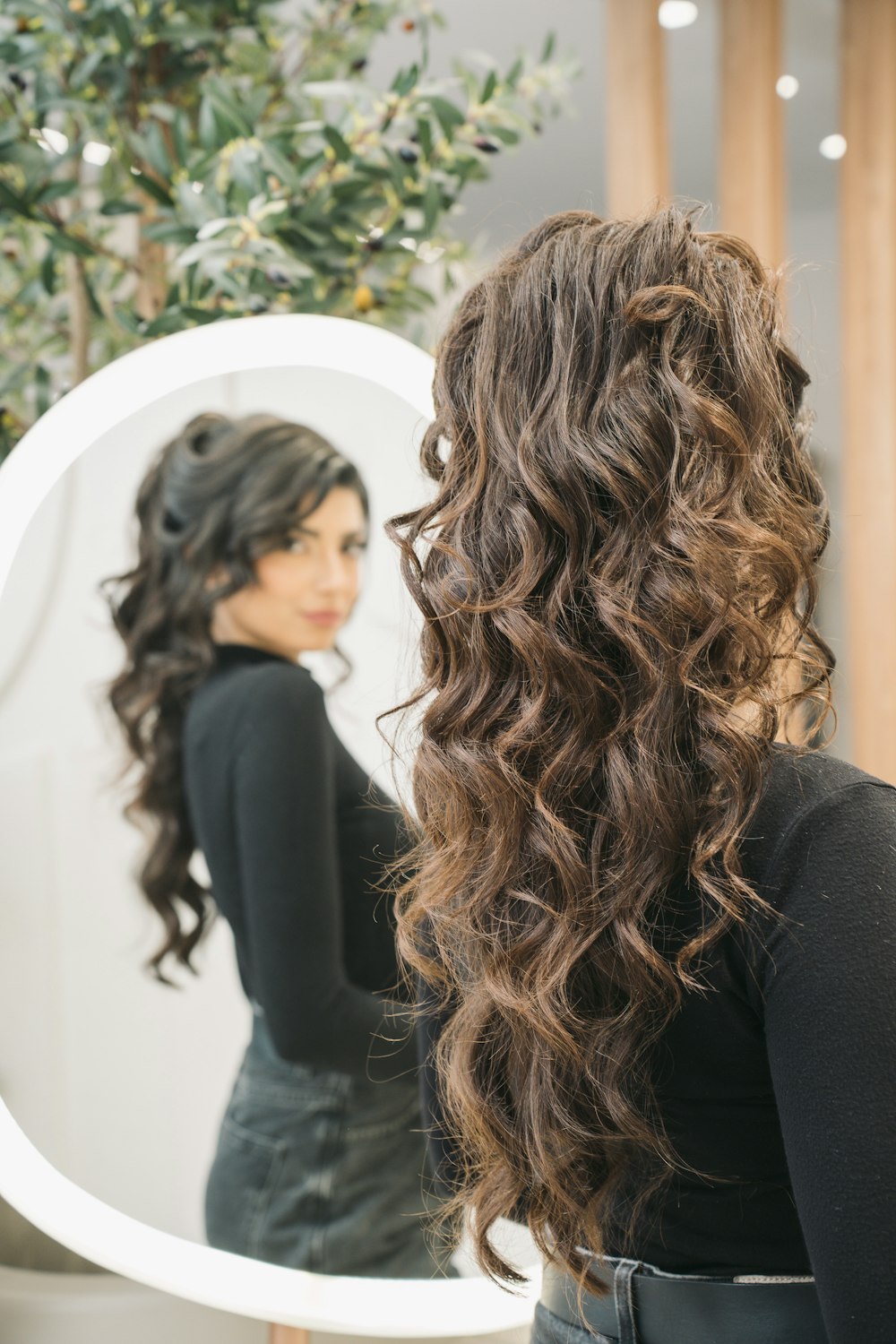 a woman standing in front of a mirror brushing her hair