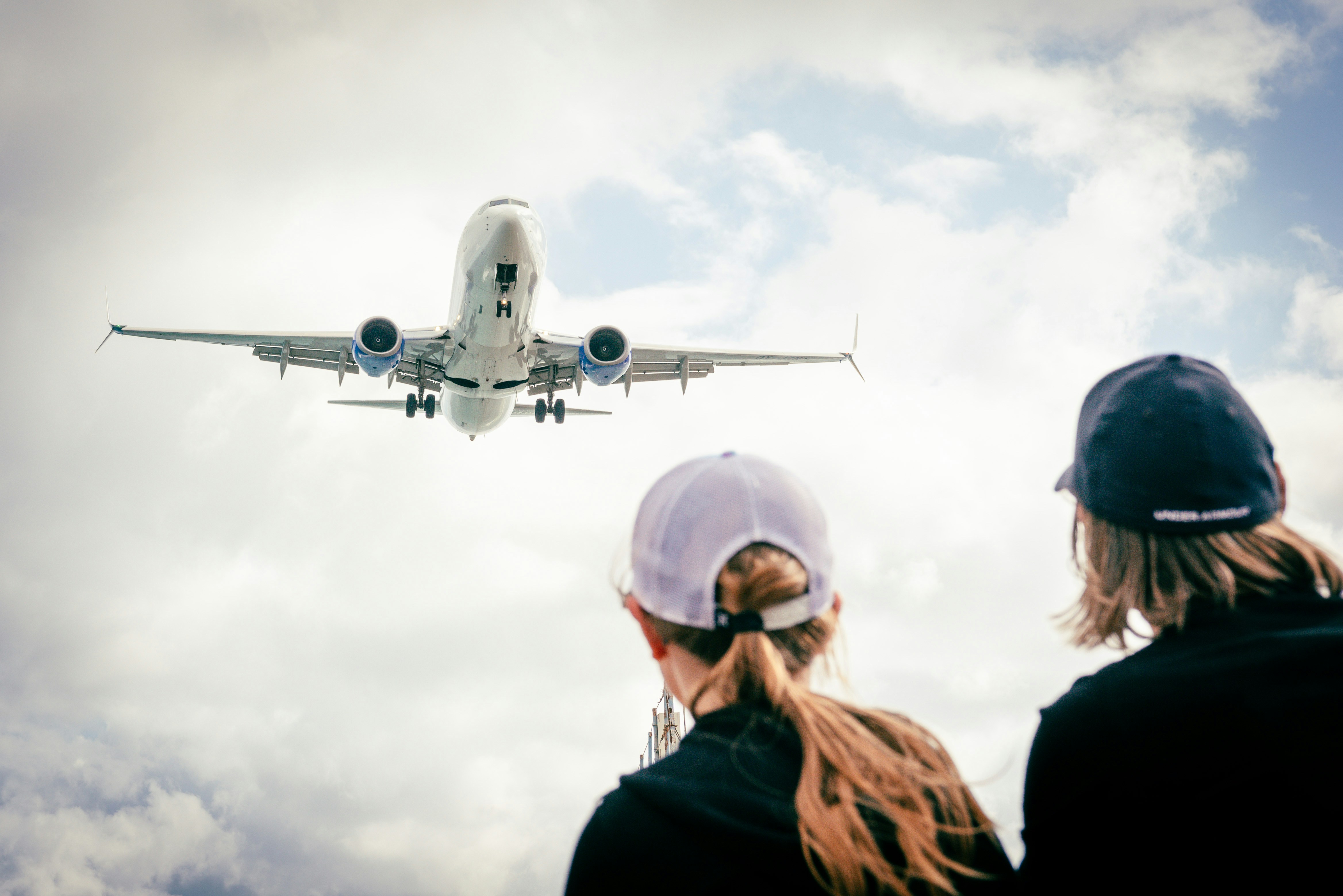two people looking at an airplane in the sky