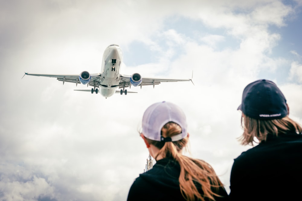 two people looking at an airplane in the sky