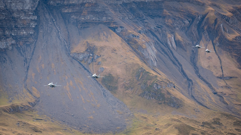 a group of fighter jets flying over a mountain