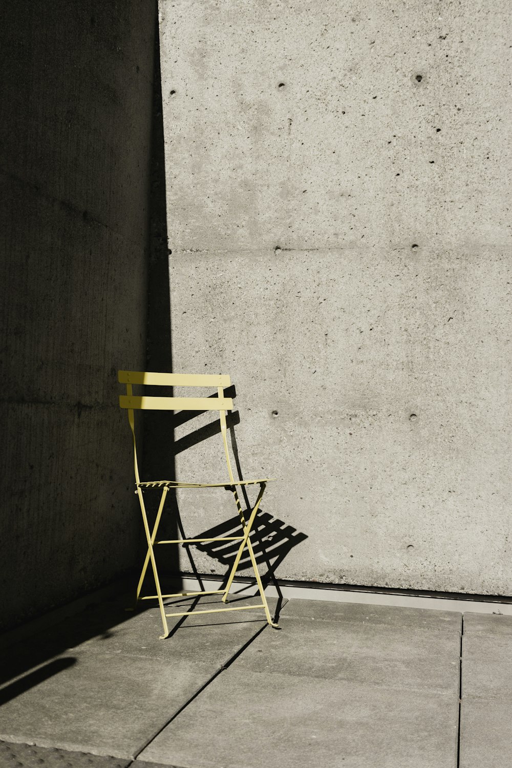 a yellow chair sitting in front of a concrete wall
