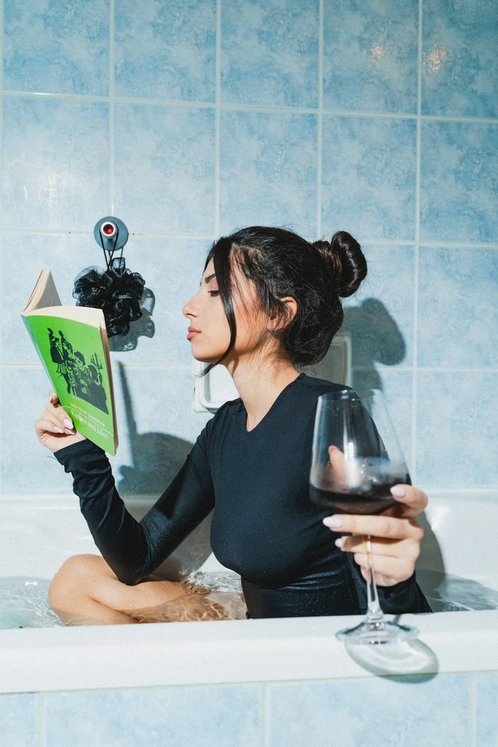 a woman sitting in a bathtub reading a book
