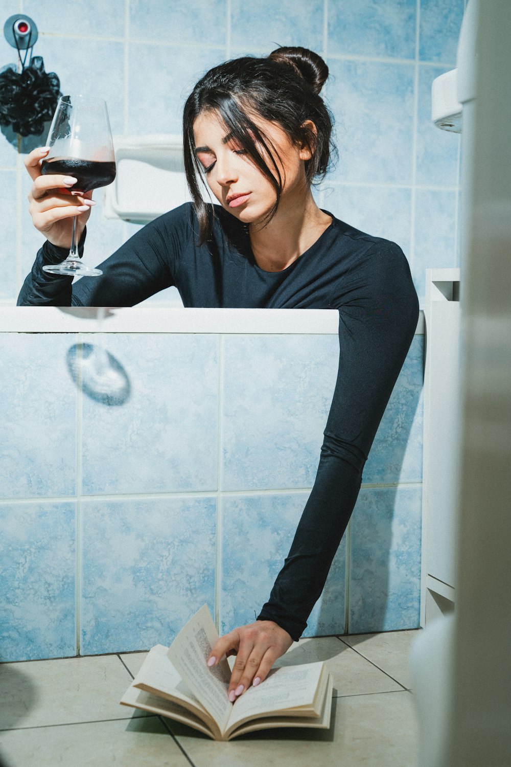 a woman holding a glass of wine and reading a book