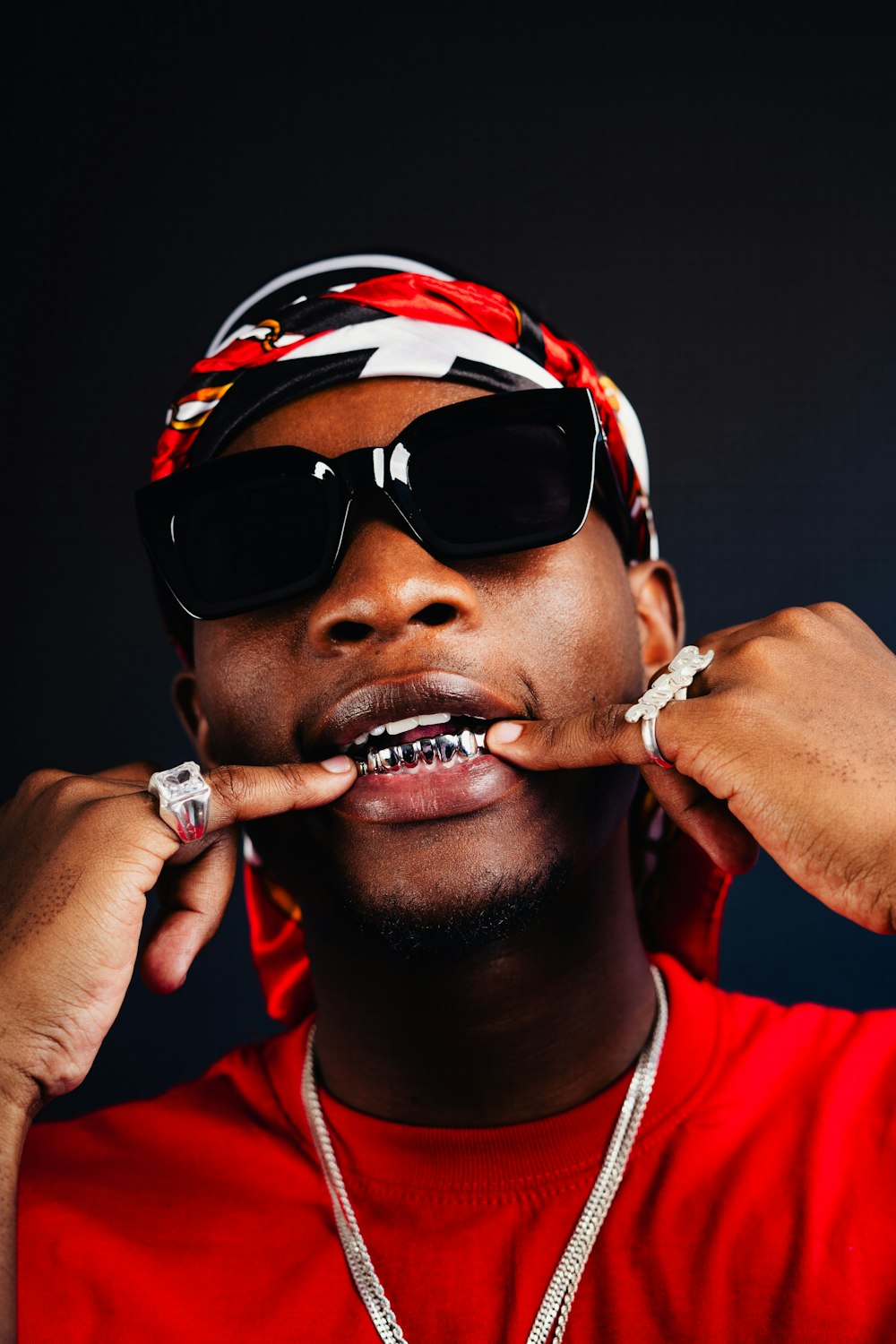 a man wearing sunglasses and a bandana brushing his teeth