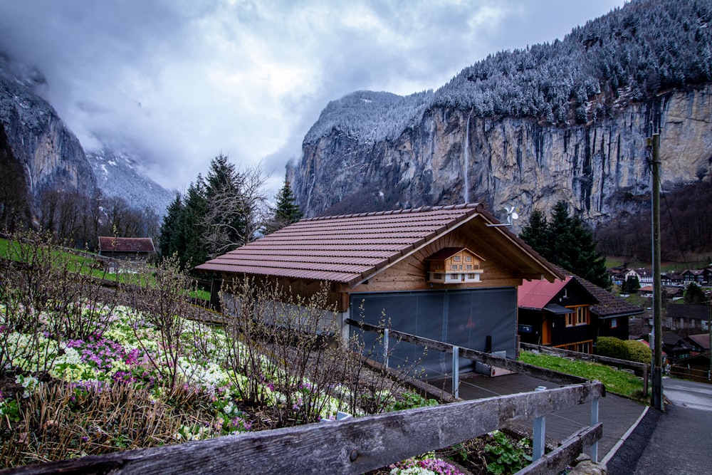 a wooden house with a brown roof and a mountain in the background