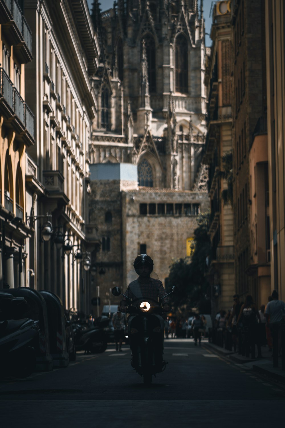 a man riding a motorcycle down a street next to tall buildings