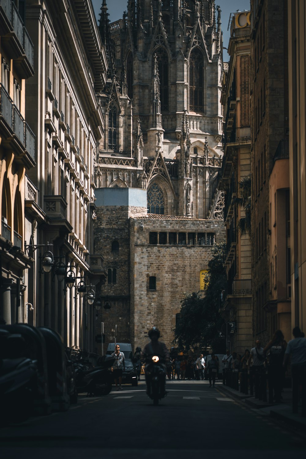 a man riding a motorcycle down a street next to tall buildings