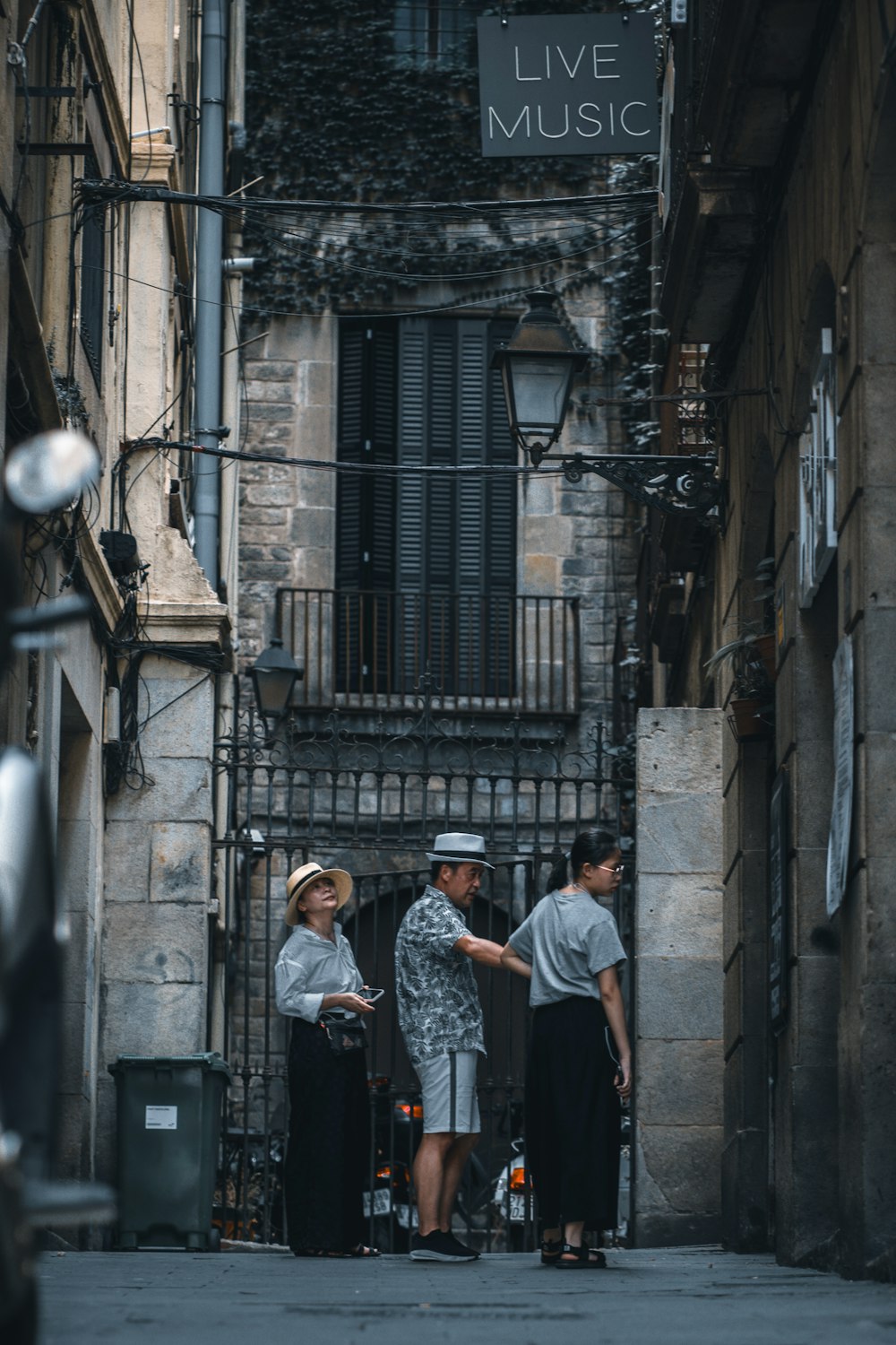 three people standing in an alleyway talking to each other