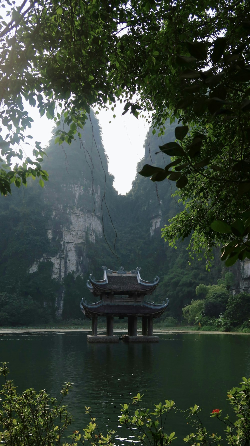 a pagoda in the middle of a lake surrounded by mountains