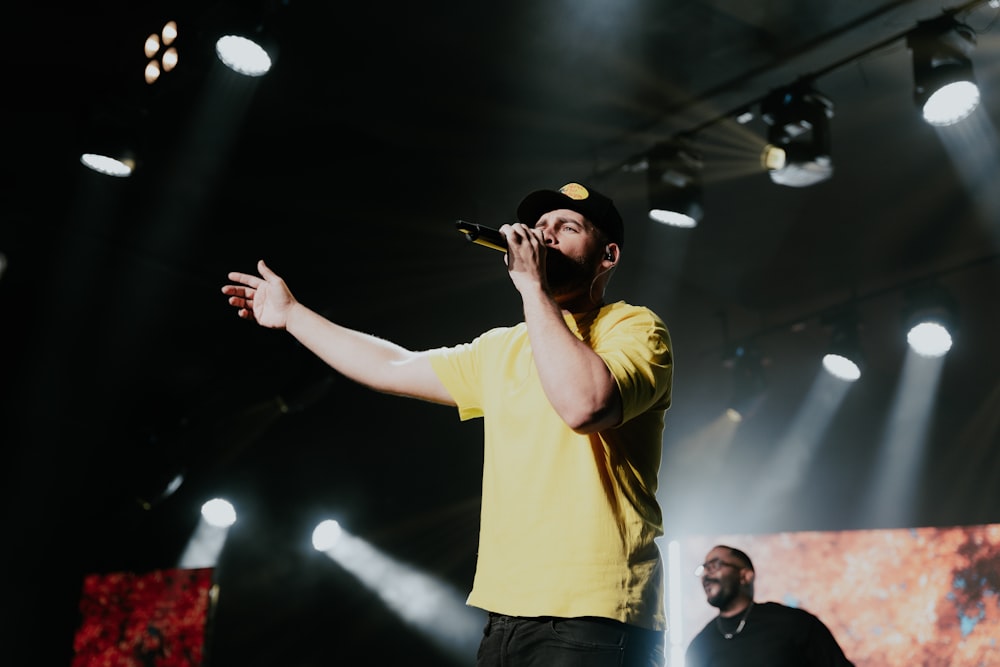 a man in a yellow shirt singing into a microphone