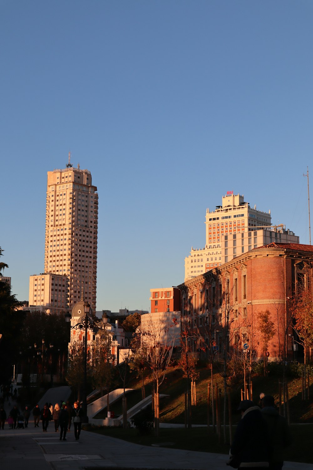 a group of people walking down a street next to tall buildings