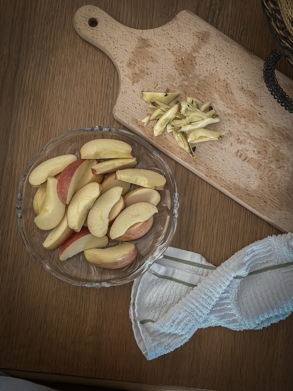 a wooden cutting board with a cutting board and a bowl of apples