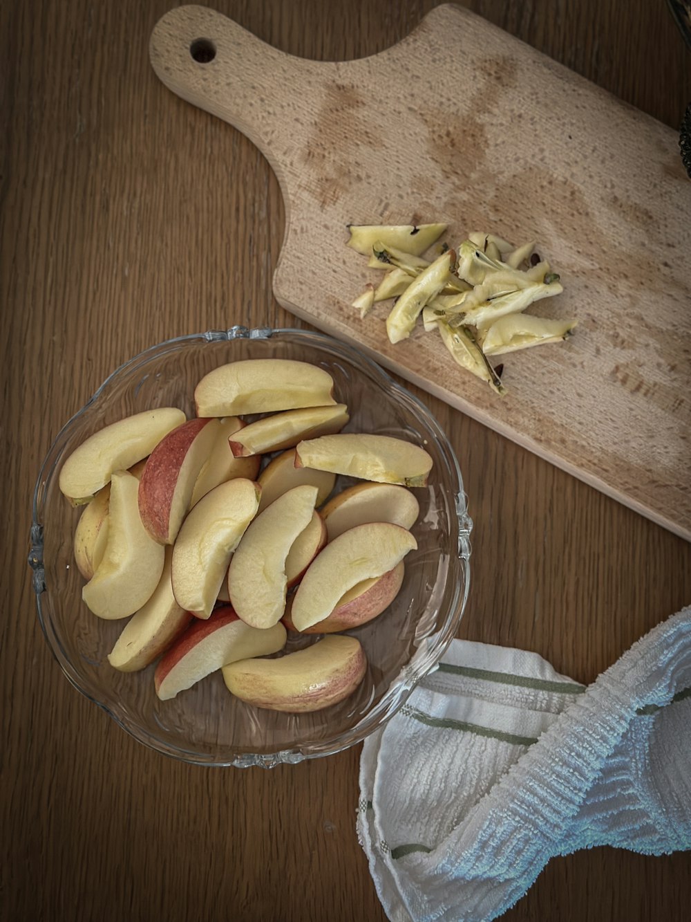 a bowl of sliced apples next to a cutting board