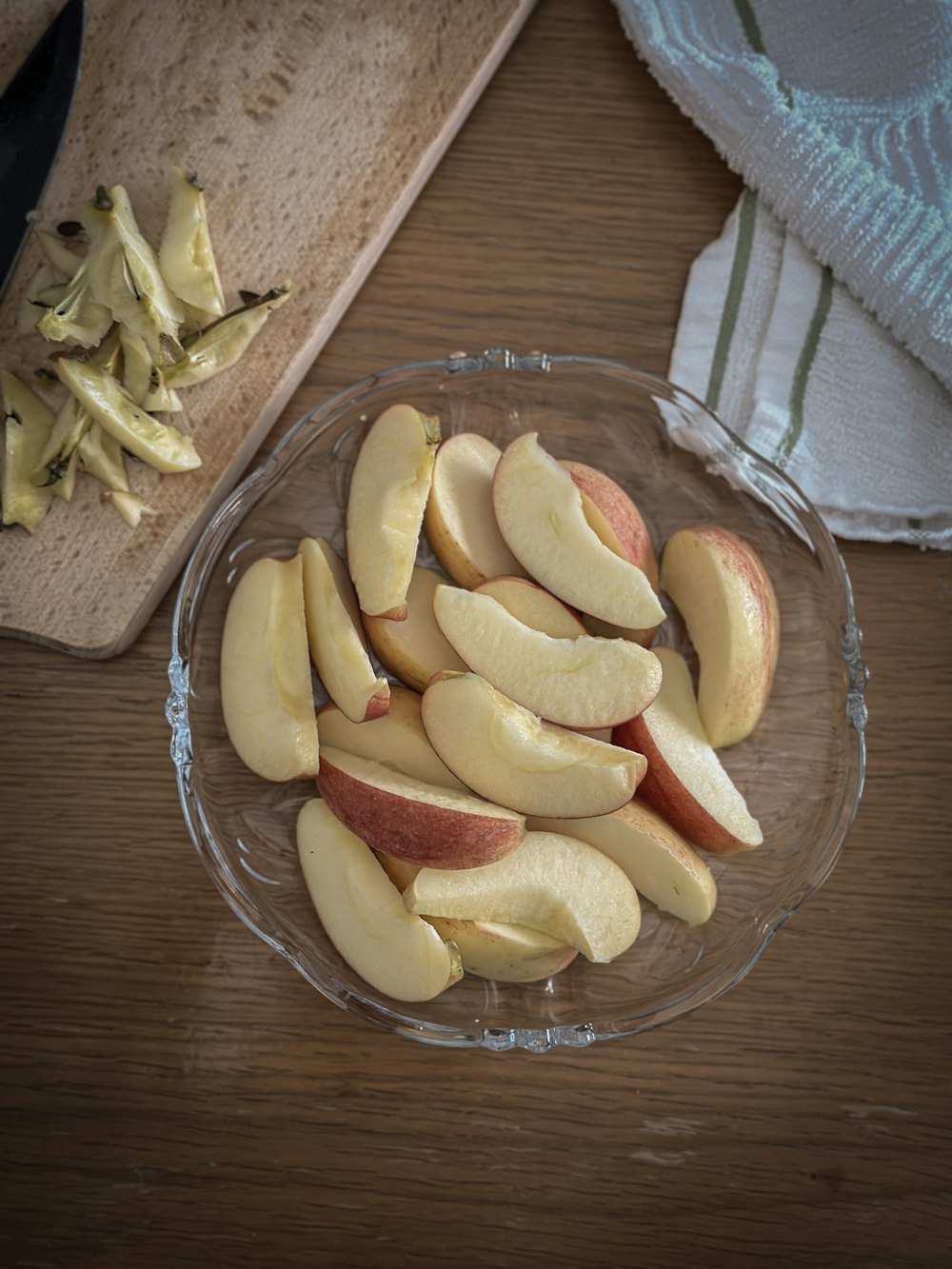 a glass bowl filled with sliced apples on top of a wooden table