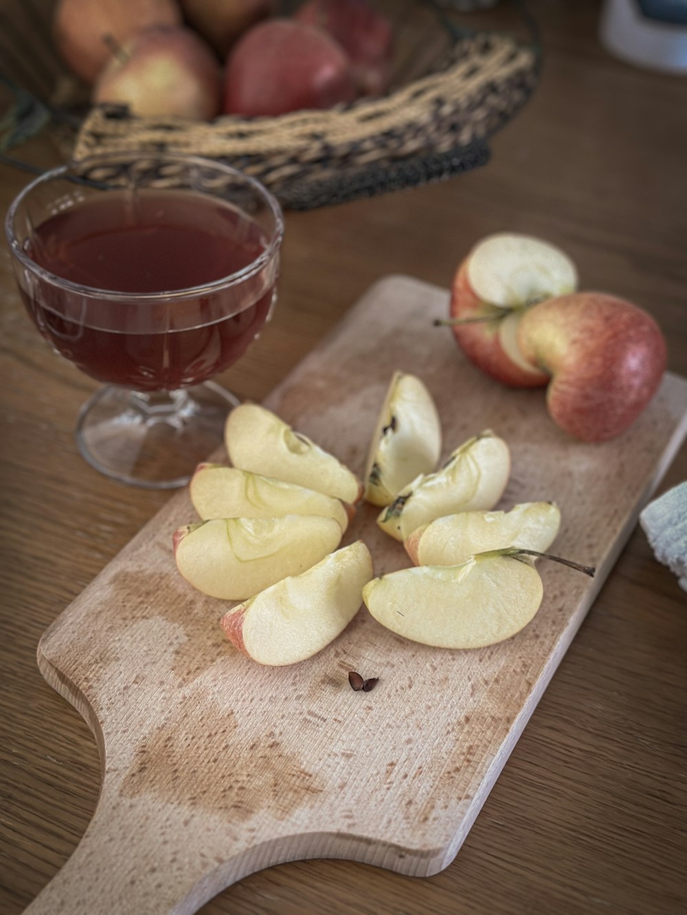 a wooden cutting board topped with apples next to a glass of wine