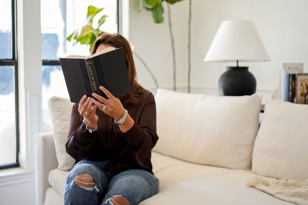 a woman sitting on a couch reading a book