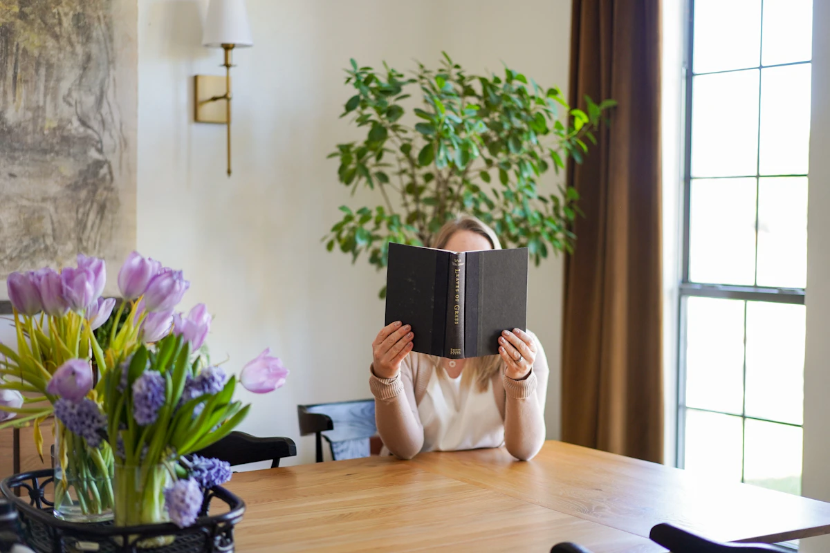 Mujer leyendo junto a flores y plantas con el rostro oculto