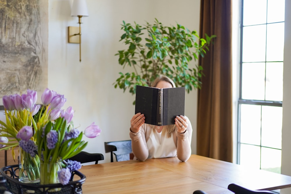 a woman sitting at a table reading a book