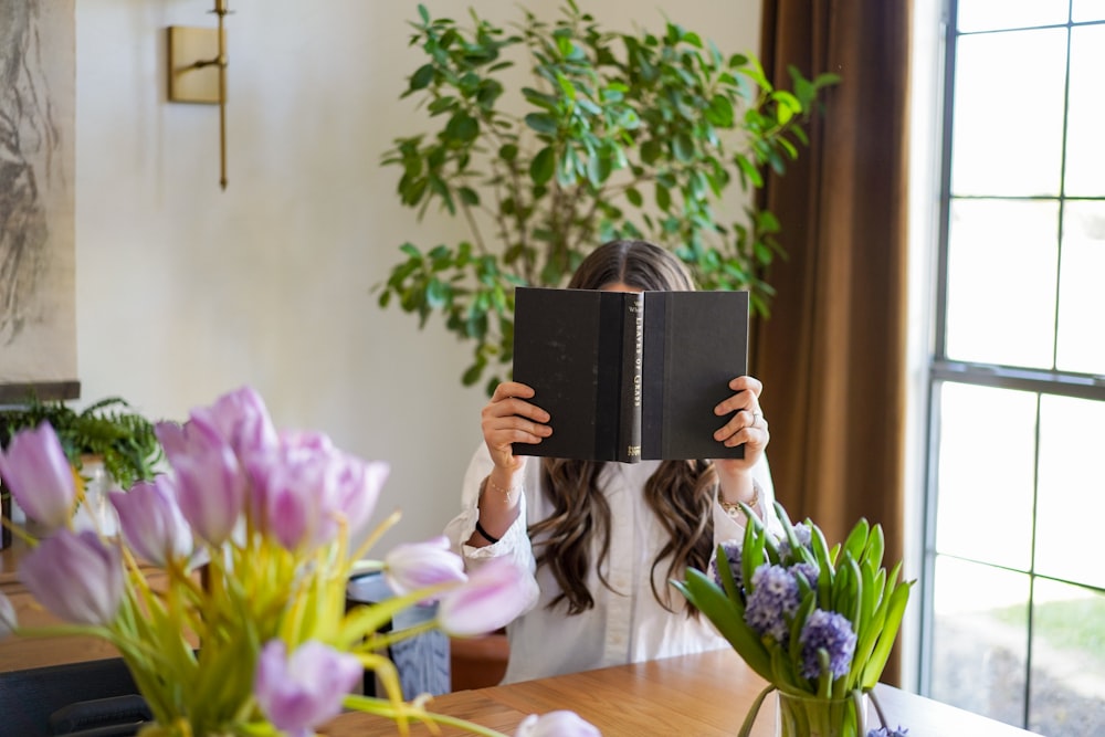 a woman sitting at a table reading a book