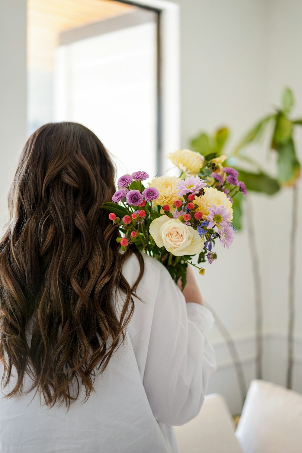 a woman holding a bouquet of flowers in front of a mirror