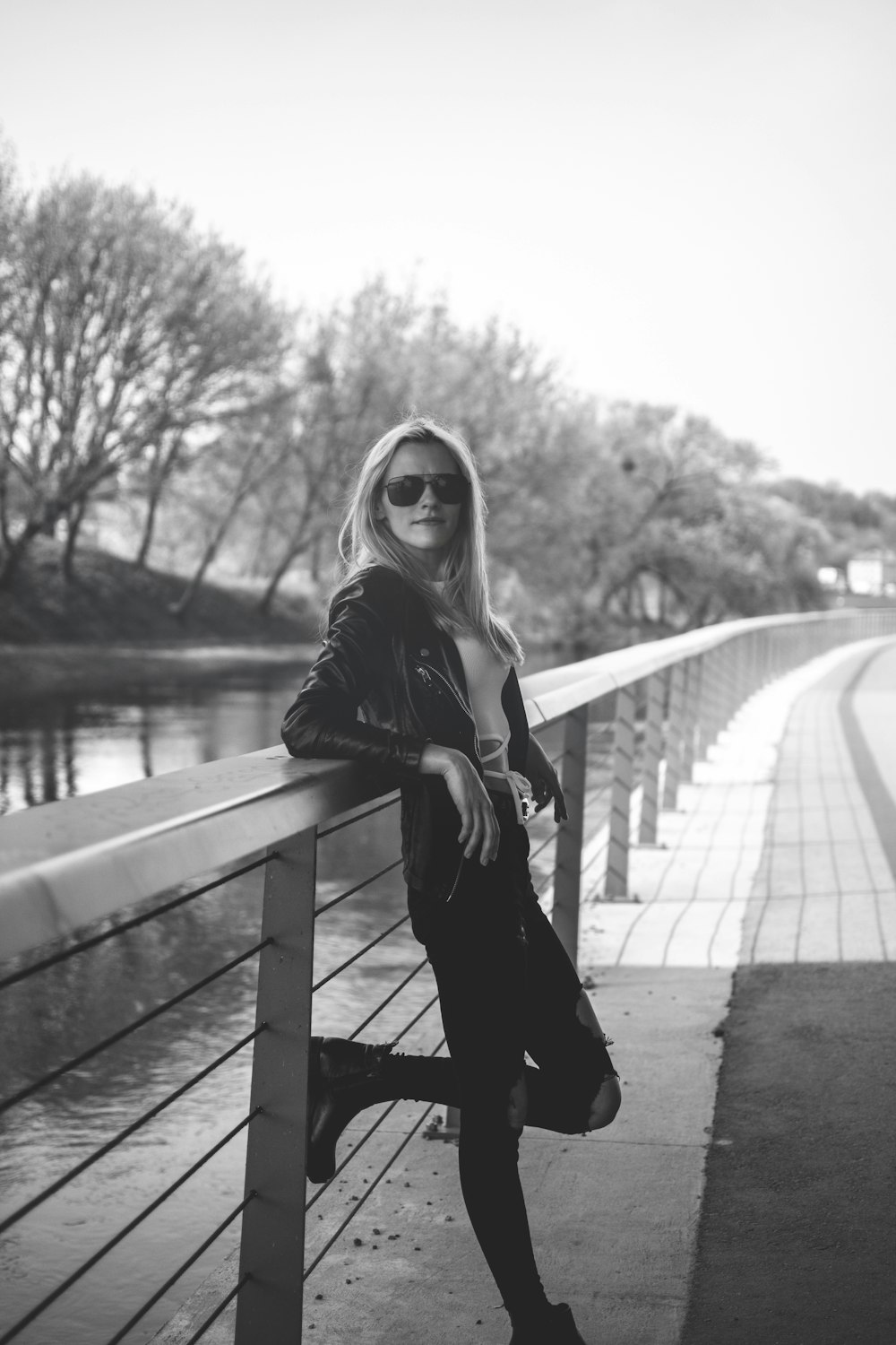 a woman leaning on a rail next to a body of water