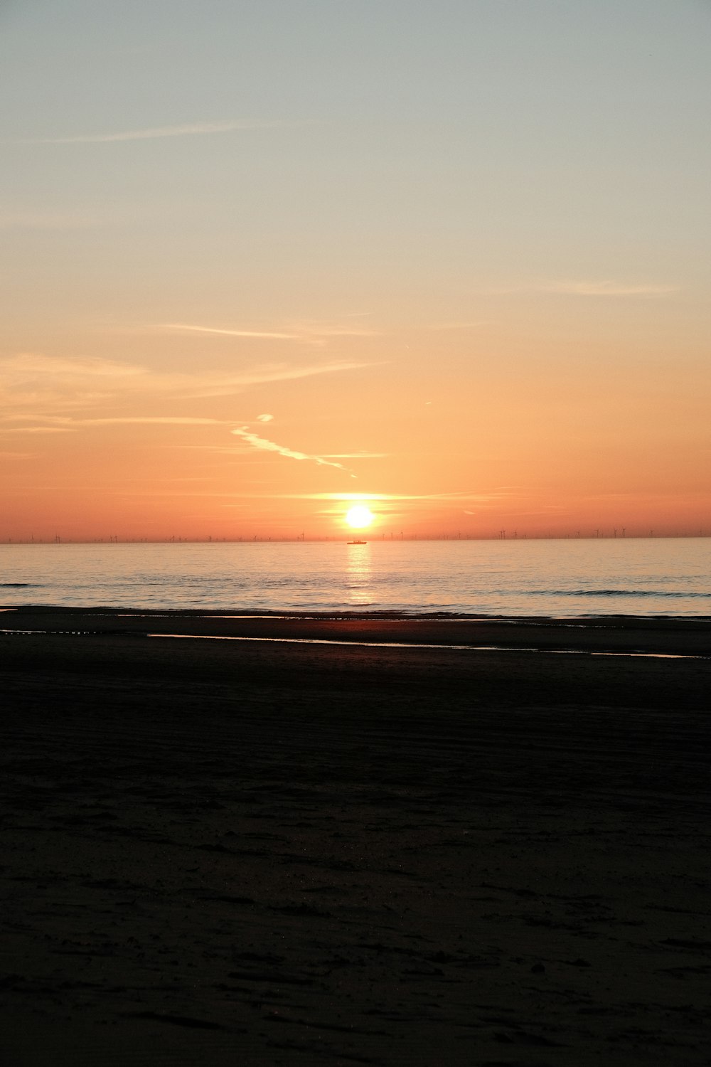 the sun is setting over the ocean on the beach