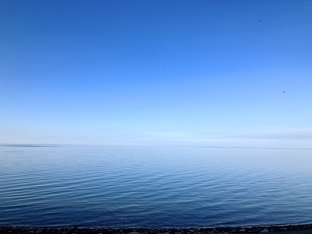 a large body of water sitting under a blue sky