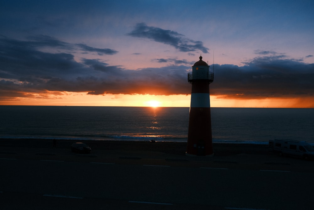 a light house sitting on the side of a road next to the ocean