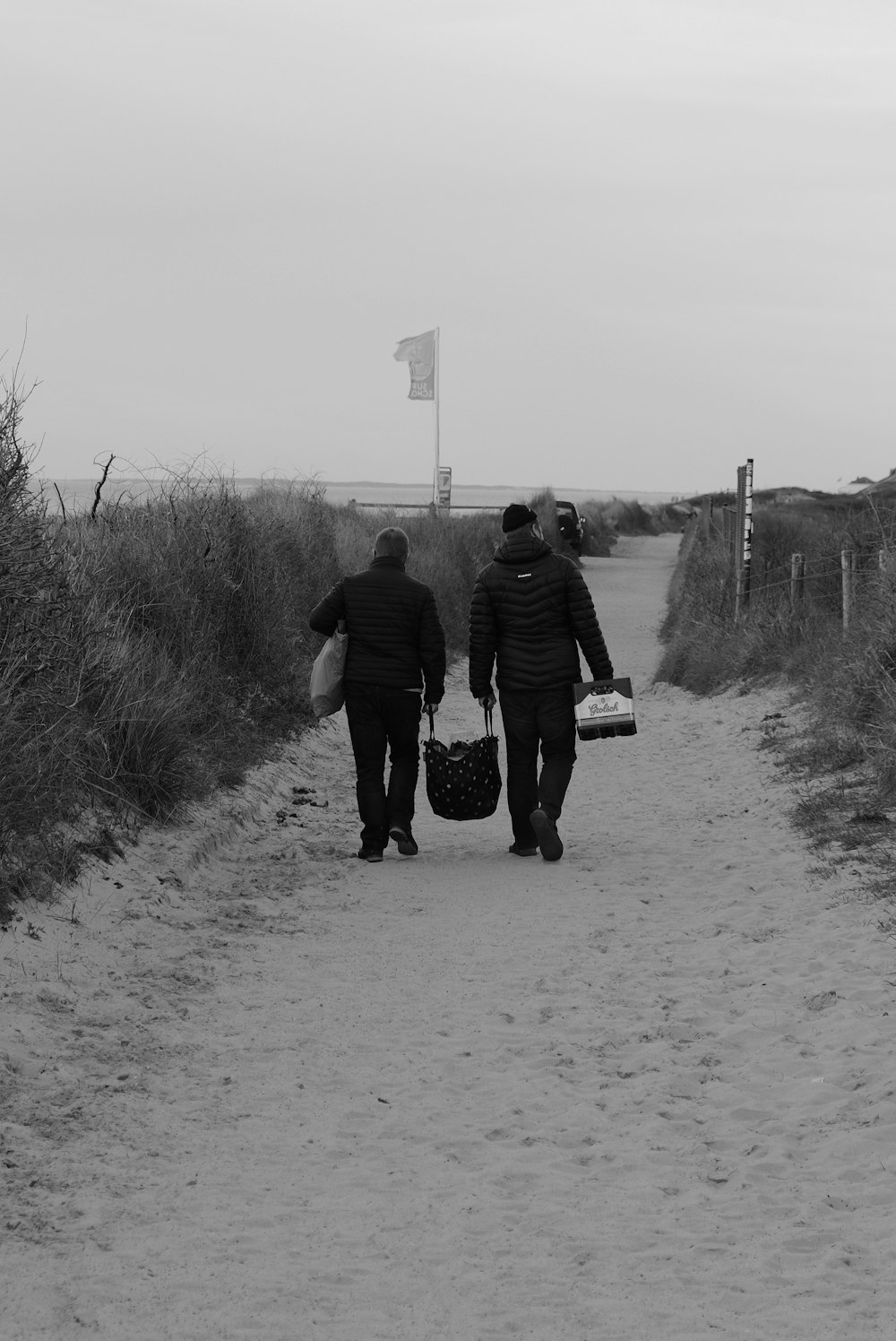 a couple of people walking down a dirt road