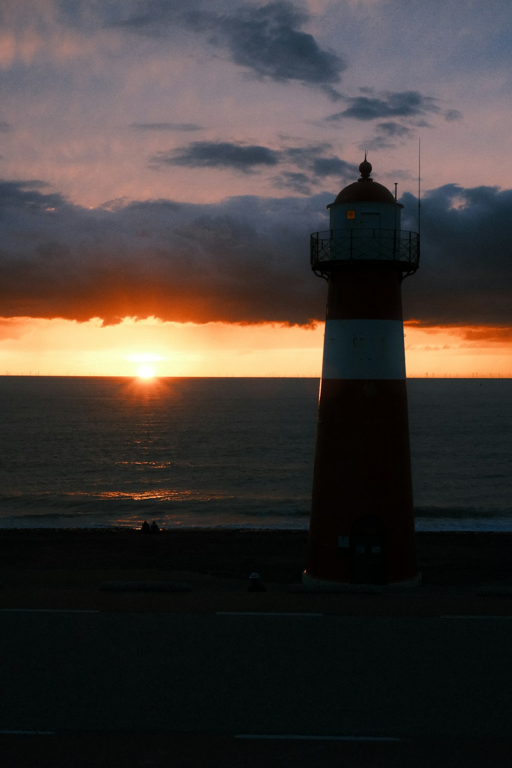 un phare assis sur le bord d’une route près de l’océan
