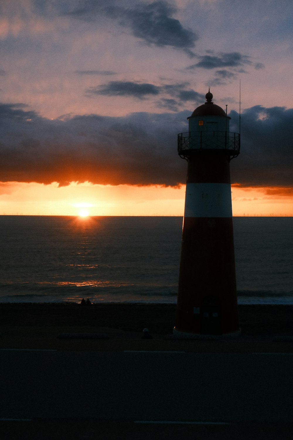 a light house sitting on the side of a road near the ocean