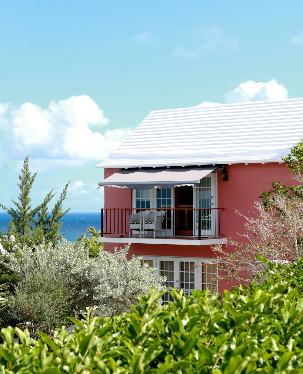 uma casa vermelha com um telhado branco e uma varanda