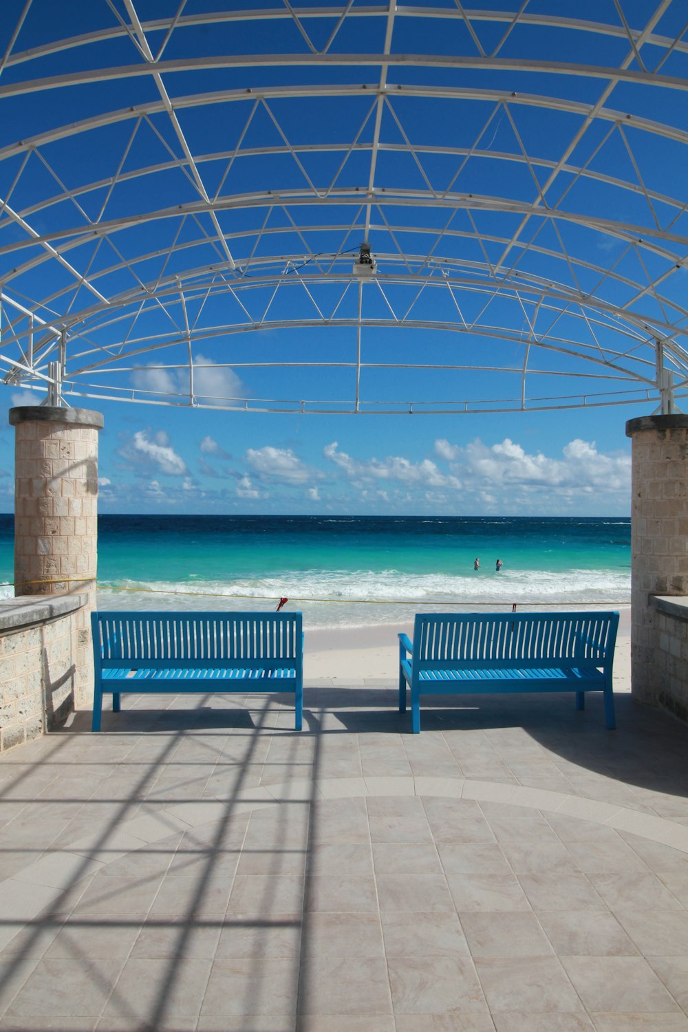 a couple of blue benches sitting on top of a sandy beach