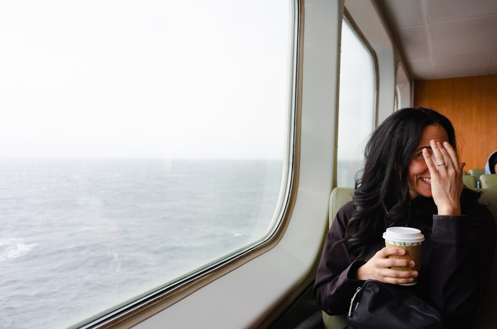 una mujer sentada en un tren sosteniendo una taza de café