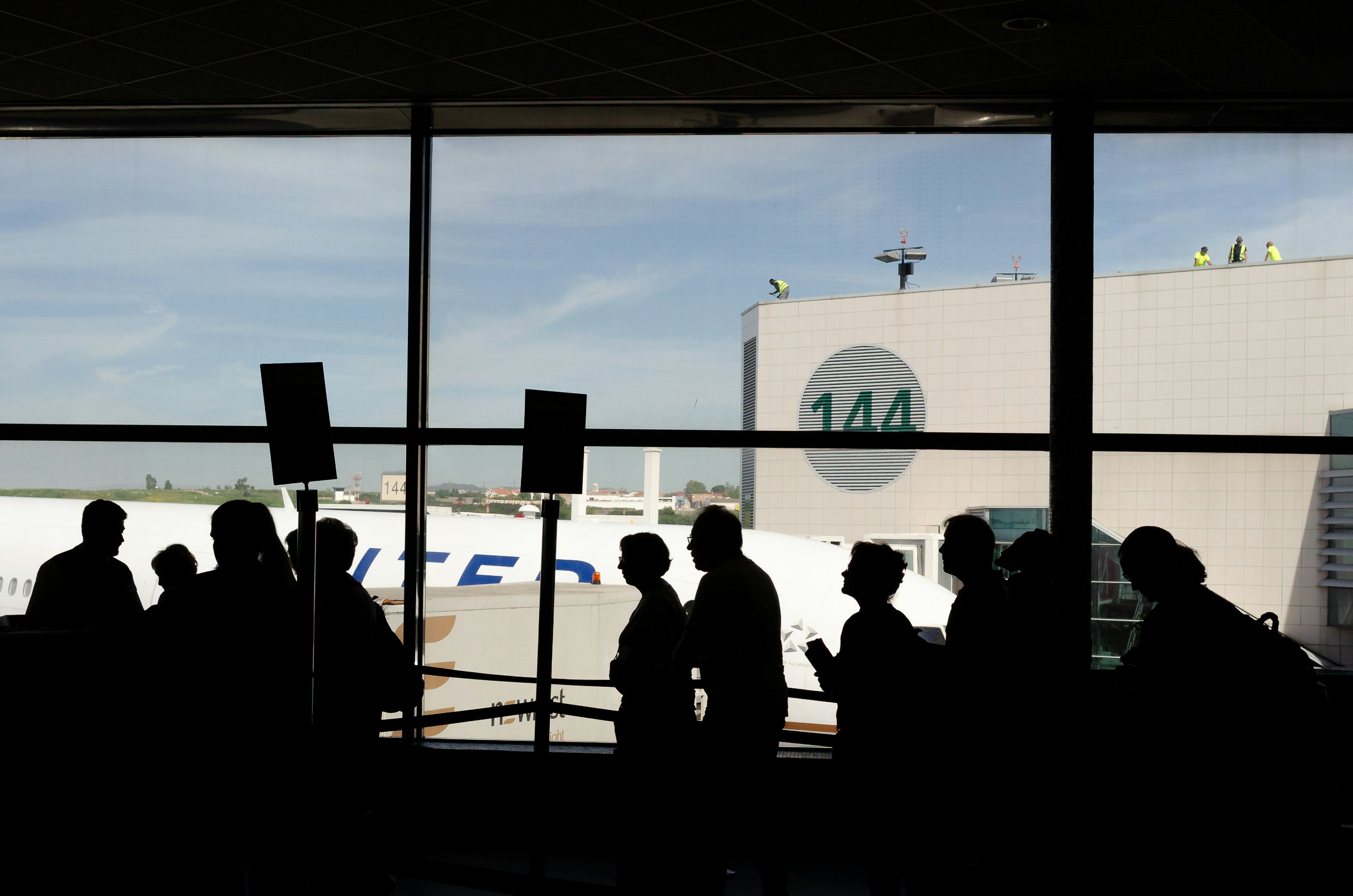 a group of people standing in front of an airport window, 