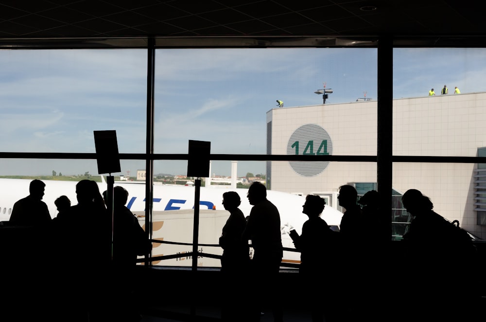 a group of people standing in front of an airport window