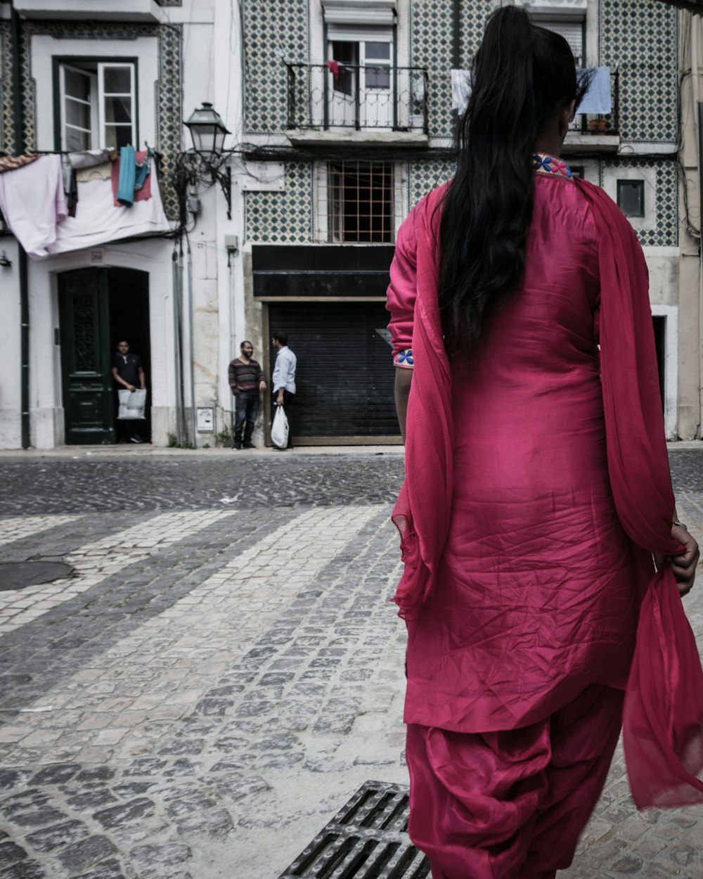 a woman in a pink dress walking down a street
