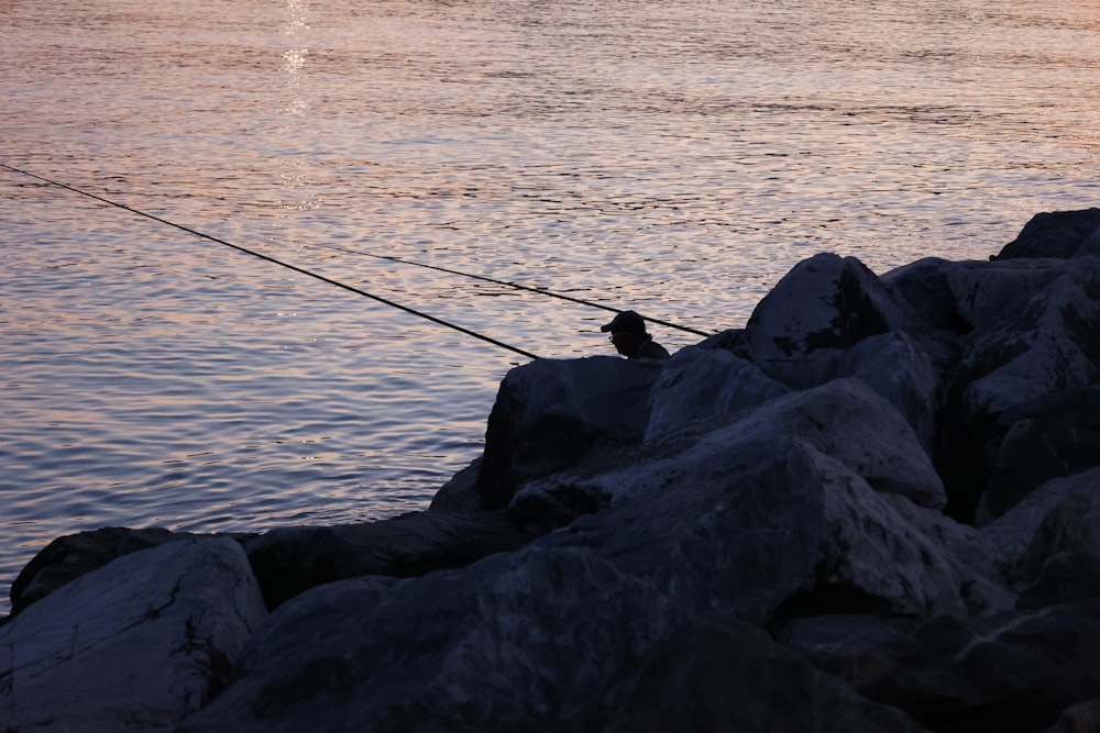 um homem pescando em um lago ao pôr do sol