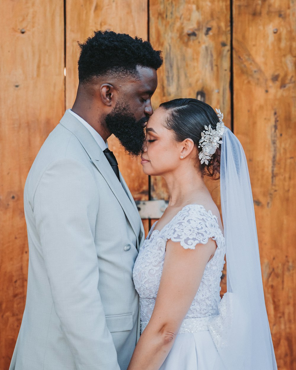 a bride and groom standing next to each other in front of a wooden wall