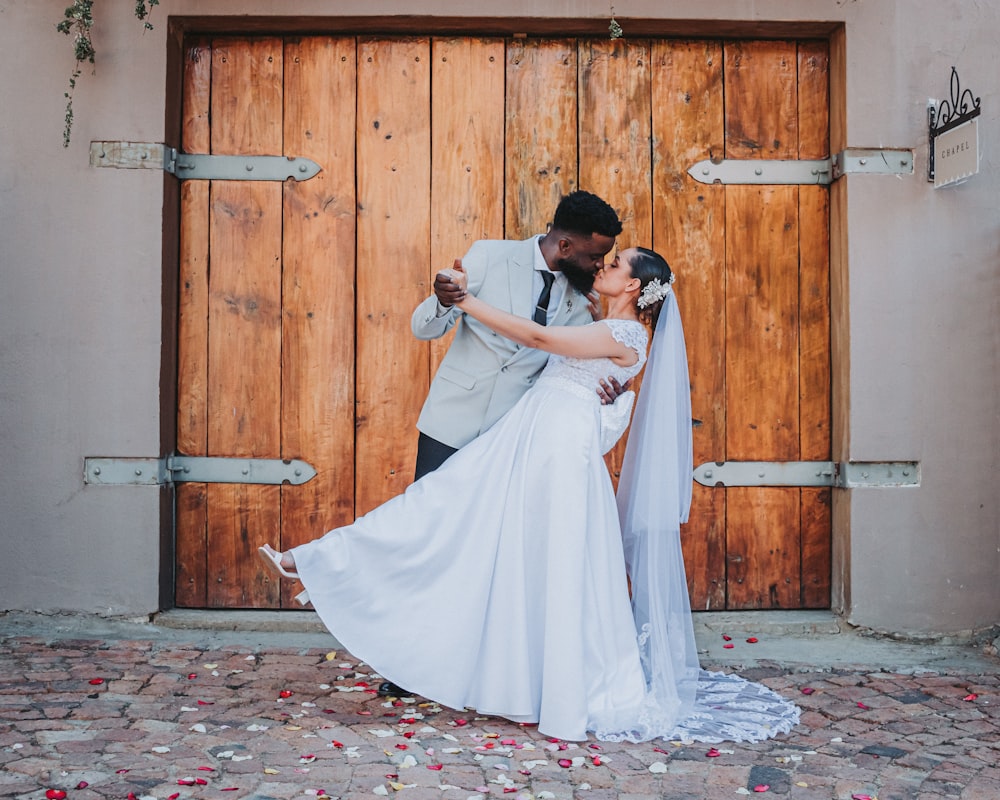 a bride and groom kissing in front of a wooden door